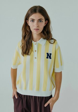 Polo a maglia con righe gialle e bianche, colletto, quattro bottoni dorati e logo 'N' blu sul petto sinistro. Presenta maniche corte.