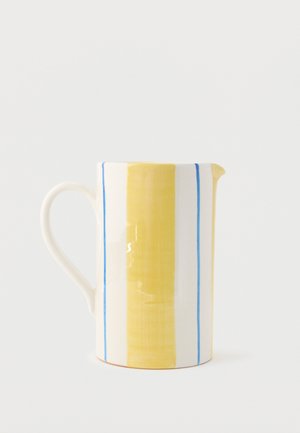 Pichet en céramique avec des rayures verticales jaunes et bleues, une anse courbée à gauche et un petit bec à droite.