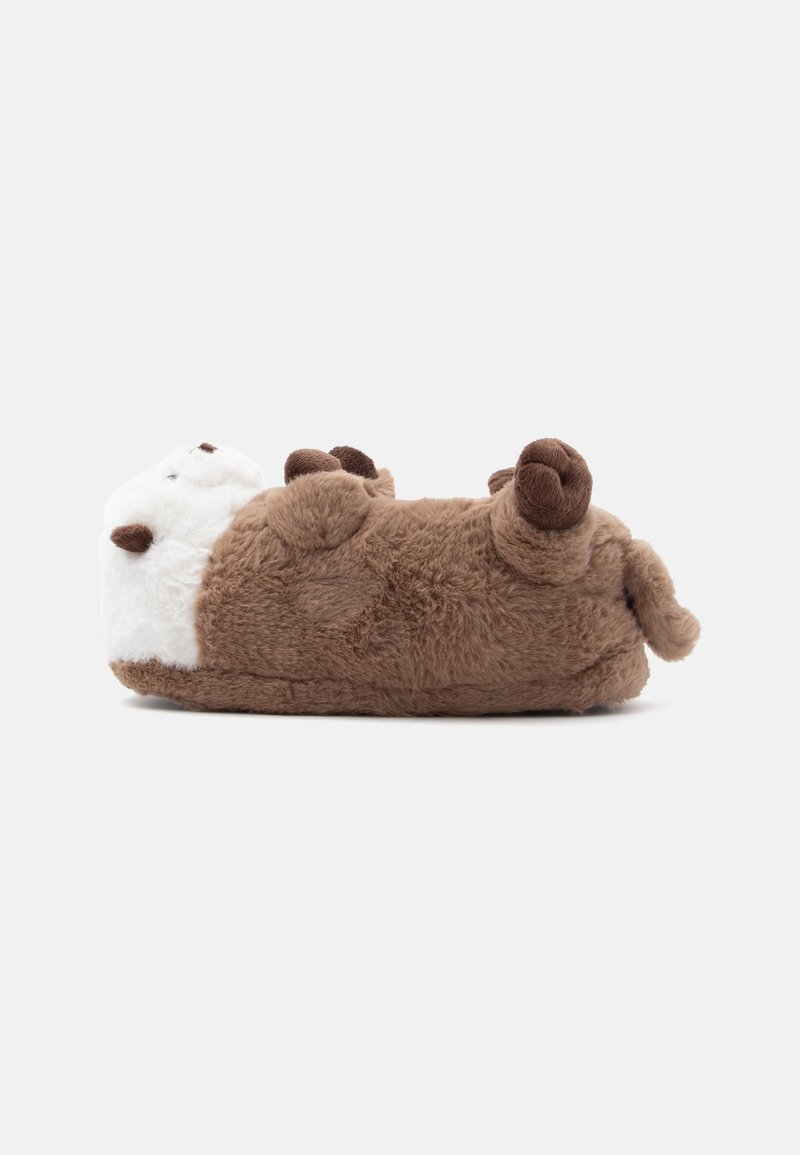 Chien en peluche marron et blanc allongé sur le dos les pattes en l'air, texture douce, isolé sur un fond gris clair.