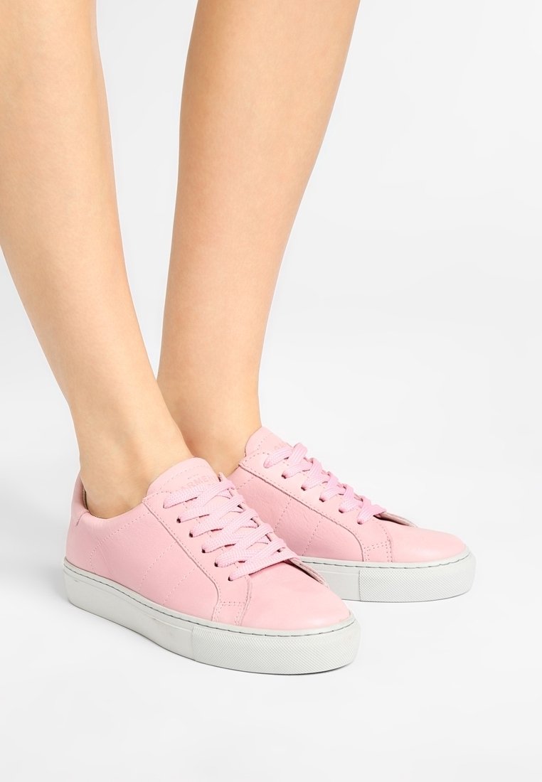 Růžové kožené tenisky s kulatou špičkou, plochou bílou gumovou podrážkou a odpovídajícími tkaničkami. Boční panely mají jemné prošívané detaily.