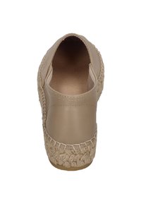 Beige leather shoe with a woven jute-like outsole, rounded toe, and smooth texture. Minimal stitching and a slip-on design.