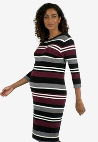Vestito a maglia a costine con strisce orizzontali in bordeaux, nero, grigio e bianco. Maniche a tre quarti e silhouette aderente.