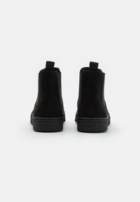 Black suede ankle boots with elastic side panels, pull tabs, and textured rubber soles. Smooth finish and minimalistic design.