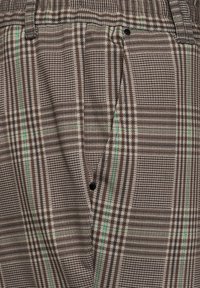 Tissu à carreaux brun avec des accents verts, présentant une surface texturée et un design plissé. Comprend un petit détail de bouton noir.