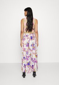 Adīts topiņš ar argaili pārklājumu bēšā, rozā un brūnā krāsā; kombinēts ar plūstošu baltu svārku, kuram ir rozā un violeti ziedu raksti.