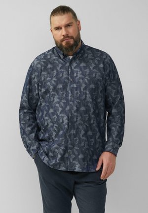 Blauw overhemd met knopen en een donker geometrisch patroon, met een kraag en knoopsluiting, gecombineerd met donkere broeken.