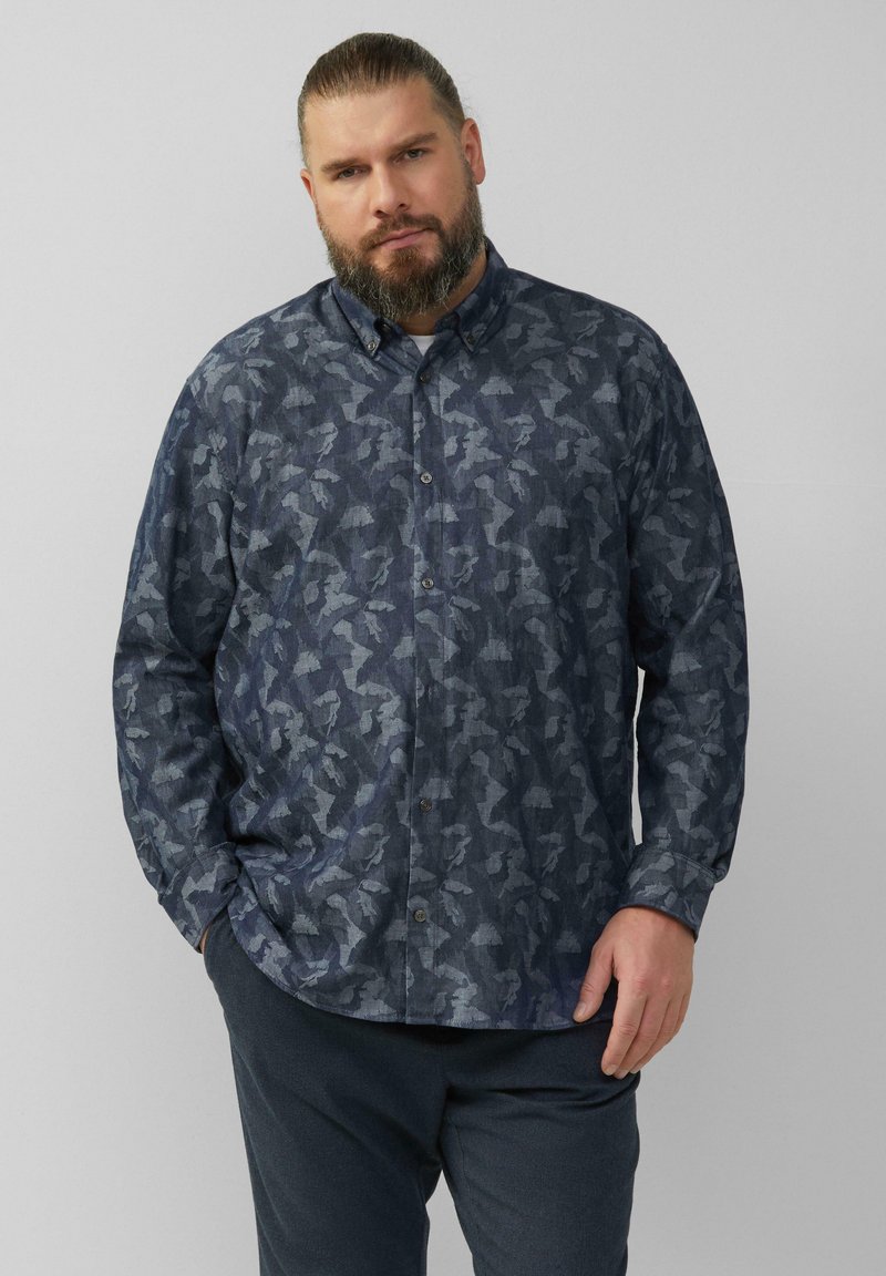 Blauw overhemd met knopen en een donker geometrisch patroon, met een kraag en knoopsluiting, gecombineerd met donkere broeken.
