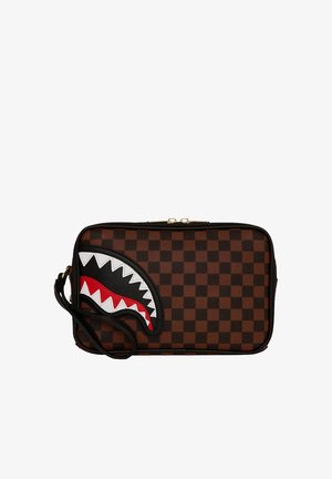 Bolso de mano rectangular de cuadros marrones y negros con correa negra, que presenta un diseño de boca de tiburón en blanco, rojo y negro en el frente.