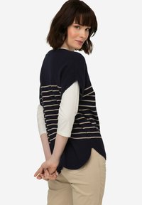 Námořnický a krémový pruhovaný svetr s krátkými rukávy a zakřiveným lemem, nabízející volný střih a měkkou pletenou texturu.