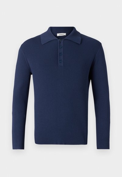 Tengeri kék bordázott hosszú ujjú pólóing lapos gallérral, három gombbal és texturált anyaggal. Egyszerű dizájn és fitted sziluett.