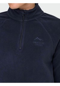 Mornarska flis jakna s visokim ovratnikom, zatvaranjem na pola munje i izvezenim logotipom. Mekana tekstura i minimalistički dizajn.