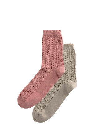 Deux paires de chaussettes tricotées : une en rose poussiéreux avec un motif côtelé, et une autre en gris clair avec une texture tissée. Chacune a un revers côtelé.