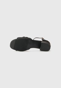 Sorte, flate såler sandaler med teksturert gummibunn, elegant design, tynn ankelreim med gullhardware og mykt stoffoberste.