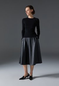 Black ribbed knit top with long sleeves, paired with a flowing black leather midi skirt and pointed black heels. Smooth texture, clean lines.