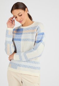 Maglione leggero a maglia di colore crema con motivi a quadri blu e pesca, con polsini e orlo a coste, scollatura rotonda e texture morbida.