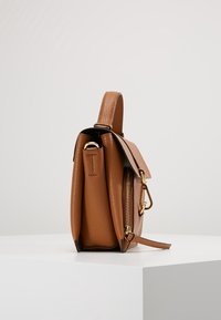 Borsa a mano in pelle marrone chiaro con finitura texture, dettagli in metallo dorato, manico superiore e tasca laterale con zip. Design compatto e rettangolare.