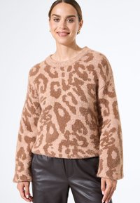 Fluffy, pink Leopardenmuster-Pullover mit rundem Ausschnitt und langen Ärmeln, kombiniert mit dunklen Lederhosen. Weicher Stoff und entspannter Schnitt.