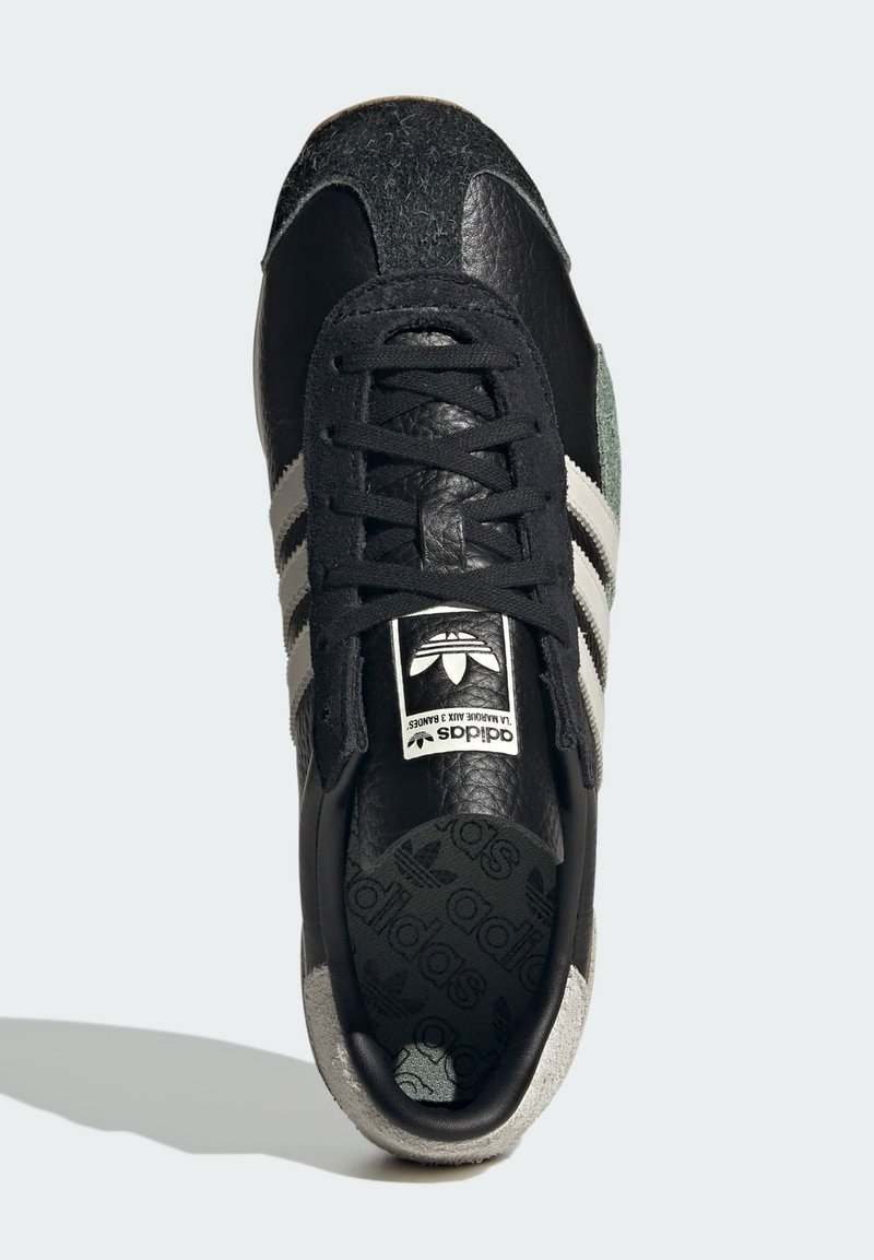 Czarno-szare sneakersy z skórzanym i filcowym wykończeniem, z trzema białymi paskami, markową etykietą na języku i wzorzystą wkładką.