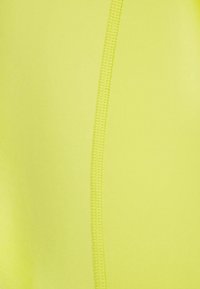 Tela atlética amarilla con una textura suave, con costuras visibles a lo largo de una costura para mayor durabilidad.