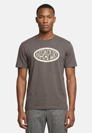 Man draagt een grijs T-shirt met korte mouwen met een wit ovaal logo met de tekst "Napapijri" op de borst en grijze gestructureerde broek.