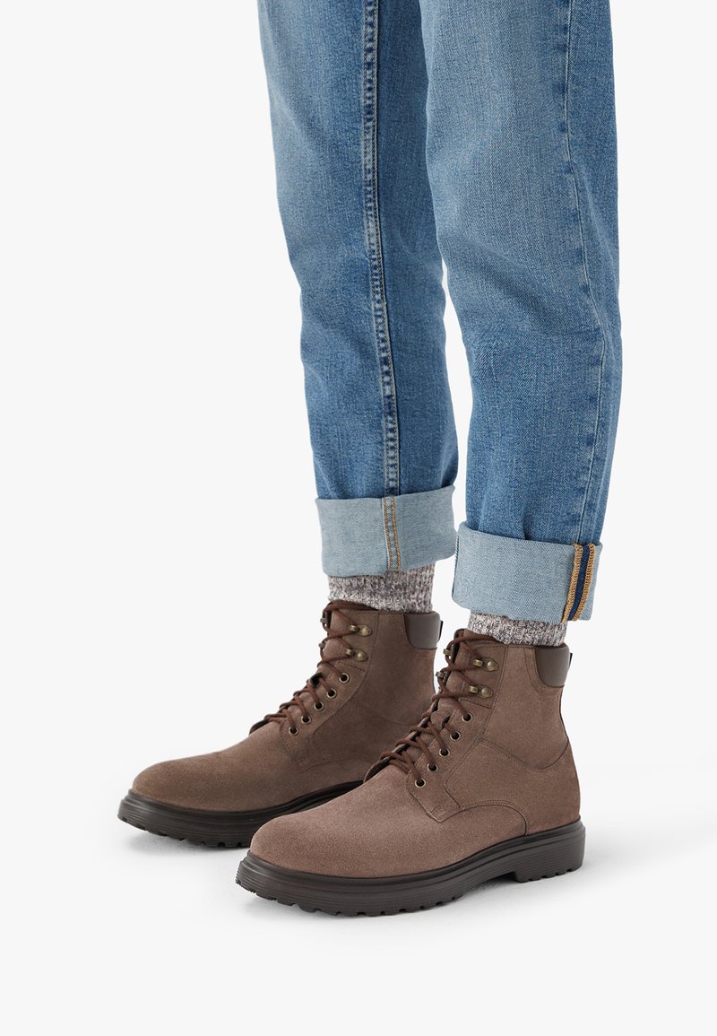 Prunat suede'ist pahklahka, ümar varba, nööridega disain, polsterdatud krae ja kummitald. Kandma helesiniseid, paeltega teksaseid ja mustrilisi sokke.