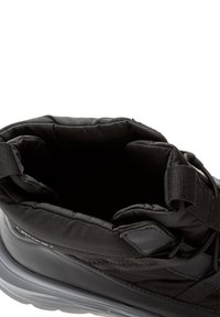 Čierna zateplená zimná obuv s hrubou podrážkou a zapínaním na suchý zips, z pohľadu zhora s otvoreným vstupom, ktorý ukazuje vnútorné podšívku.