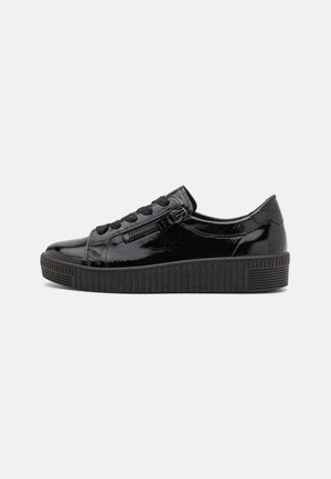 Baskets en cuir verni noir avec une semelle en caoutchouc texturé noir, un système de laçage à l'avant, et un zip sur le côté pour un accès facile.
