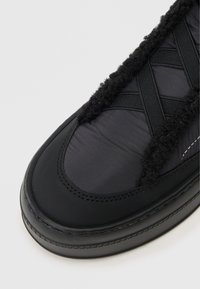 Μαύρο αθλητικό παπούτσι με υφή, πολυτελή εσωτερικό, κομψό εξωτερικό, καουτσούκ σόλα και διασταυρούμενες ελαστικές λωρίδες. Μαλακά και αφρώδη υλικά.