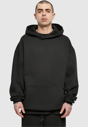 Černá mikina s kapucí, volného střihu, prostornou přední kapsou, ribbovaný lem a měkkou, texturovanou tkaninou. Jednoduchý design bez vzorů.