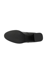 Chaussure en cuir noir avec un dessus lisse, un bout carré et une semelle plate en caoutchouc. Design minimaliste sans motifs ni éléments visibles.
