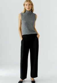 Grijze mouwloze coltrui gecombineerd met zwarte wijde broek, met een gladde textuur en een minimalistisch ontwerp, wat zorgt voor een moderne uitstraling.