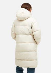Lange, crèmekleurige pufferjas met een capuchon, met oversized, gequiltte delen en een gladde, glanzende textuur.
