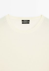 Off-white kasjmier trui met een ronde hals en ribgebreide kraag; zacht van textuur; etiket leest "Massimo Dutti," "100% kasjmier."
