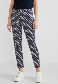 Navy broek met een diamantpatroon in roze en crème, met een fitted snit en enkel lengte, gecombineerd met witte sneakers.
