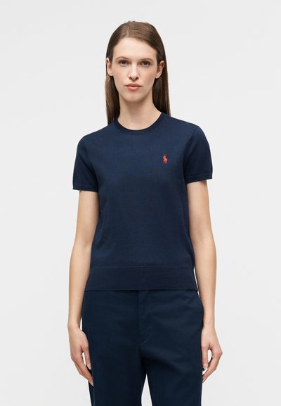 Μπλε ναυτικού χρώματος κοντομάνικη πλεκτή μπλούζα με στρογγυλή λαιμόκοψη και μικρό κόκκινο κεντητό λογότυπο στο αριστερό στήθος. Μαλακή υφή, casual εφαρμογή.