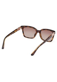 Gafas de sol de carey con marco cuadrado, lentes marrones degradados y acentos dorados en las varillas. Detalle texturizado en el hardware de las varillas.