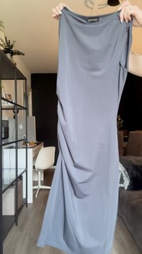 Abito maxi grigio senza maniche con una superficie liscia, design drappeggiato e scollatura rotonda. Etichetta visibile all'altezza della scollatura: "ANNA FIELD."
