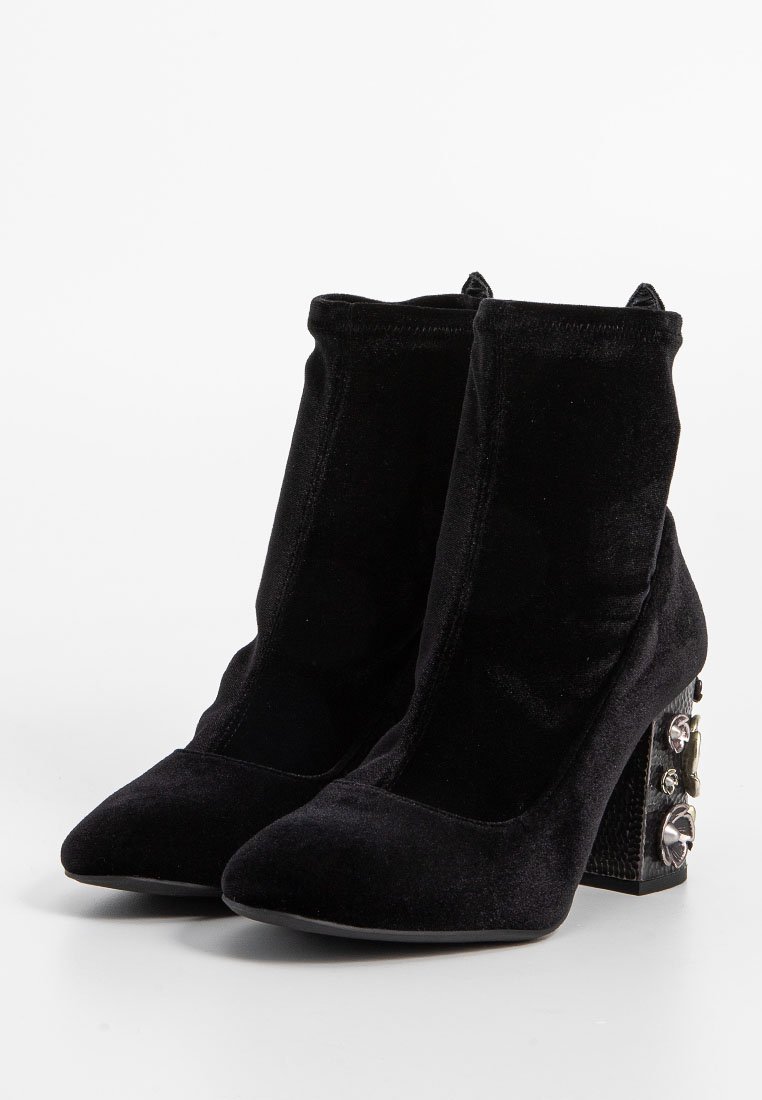 Schwarze Samt-Ankle Boots mit Absatz, die eine spitze Zehe und einen strukturierten Blockabsatz aufweisen, verziert mit dekorativen Hardware-Akzenten.