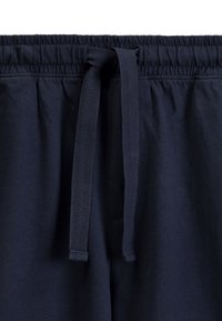 Granatowe spodnie z gumką w pasie i sznurkiem, z fakturowanym wiązaniem oraz gładkim materiałem przypominającym bawełnę. Idealne do codziennego noszenia.