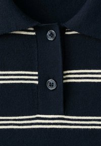 Col polo en maille bleu marine avec deux boutons foncés et rayures blanches horizontales sur la poitrine et le col.