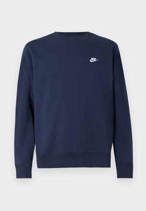 Navy zila kreklu džemperis, izgatavots no mīksta auduma, ar nelielu balto Nike logo kreisajā krūtī un ribotām aprocēm un apakšmalu.