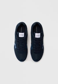 Adidași navy din materiale mixte, inclusiv plasă și suede. Prezintă un guler căptușit, șireturi plate și o etichetă de brand pe limbă.
