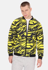 Giacca bomber gialla e nera con motivo a fantasia, con zip frontale, polsini e fondo a coste; realizzata in tessuto liscio con un design ondulato.