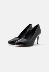 Escarpins en cuir verni noir avec un bout pointu et un talon aiguille fin. Texture lisse, design classique, sans motifs ni accents visibles.