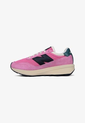 Różowo-czarny sneaker New Balance z siateczkową i zamszową cholewką, białe sznurówki, masywna beżowa podeszwa i zielona zawieszka na pięcie.