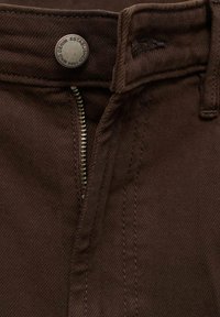 Bruine denim broek met een metalen knop met reliëftekst, een ritssluiting en nette stiksels langs de taille en de gulp.