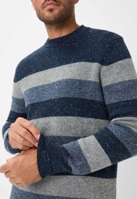 Maglione a righe navy e grigio con texture cosparsa. Presenta un colletto rotondo e polsini a coste. Realizzato in morbido tessuto a maglia.