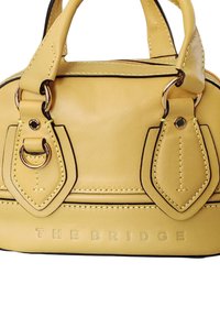 Borsa a tracolla gialla in pelle con doppio manico, dettagli neri, cuciture decorative e una superficie testurizzata. Presenta il testo in rilievo "THE BRIDGE."