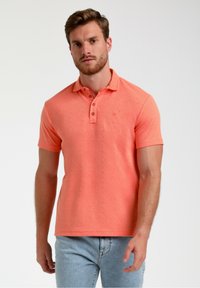 Moška kratkoslezna polo majica iz teksturiranega koralnega blaga, ki ima tri gumbe in majhen logotip na prsih.