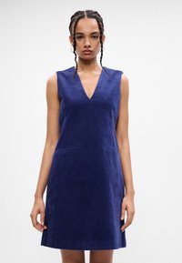Námornícke kordurové bezrukávové šaty s výstrihom do V, s dvoma prednými vreckami, rovný strih a príjemná textúra. Ideálne na neformálne nosenie.